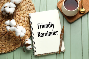 Notebook with text FRIENDLY REMINDER and pen on green wooden background - Powered by Adobe
