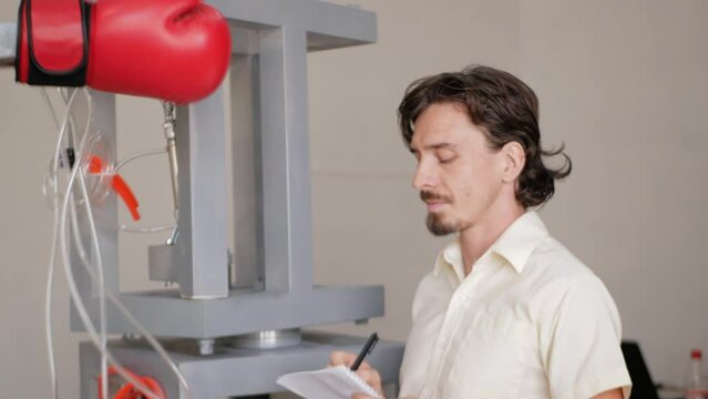 man records performance of boxer's robot. inventor monitors his device, pneumatic motor. mechanical, machine