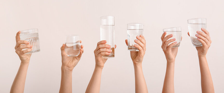 Female Hands With Glasses Of Water On Light Background