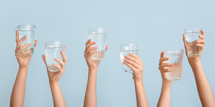 Female Hands With Glasses Of Water On Light Blue Background