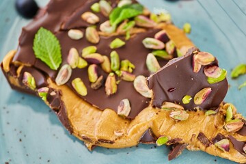 A piece of delicious chocolate cake decorated with nuts with caramel filling inside.
