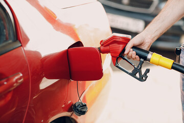Man filling fuel tank in his hand at gas station.