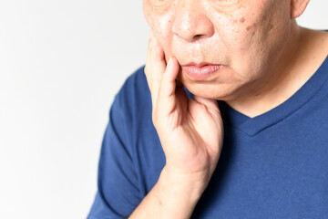 頬を抑える中高年の男性