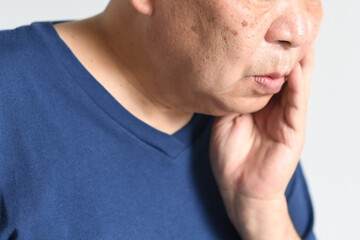 頬を抑える中高年の男性