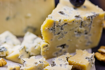 Tasty blue cheese served with grape and green on a wooden background. Dorblu cheese pieces