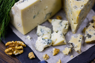 Tasty blue cheese served with grape and green on a wooden background. Dorblu cheese pieces