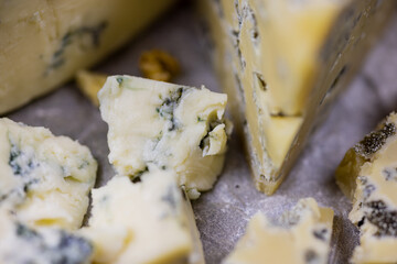 Tasty blue cheese served with grape and green on a wooden background. Dorblu cheese pieces