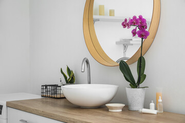 Modern sink and orchid flower on counter near white wall in bathroom - obrazy, fototapety, plakaty