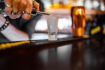 bartender pouring alcohol drink into a shot glass in bar