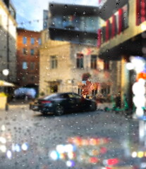  rain drops on window  modern buildings evening blurred bokeh light street decoration and illumination and Autumn leaves fall urban scene