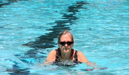 Naklejka premium Mature female senior in the swimming pool outside.