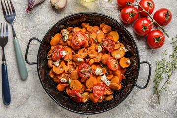 Frying pan with tasty baked vegetables on light background