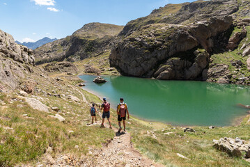 Hikers descending from Peyreget next to a lake