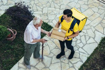 Young male volunteer delivering shopping to senior man. Donation