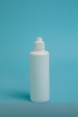 A bottle of liquid for lenses on a blue background. Mock up of liquid for lenses
