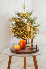 burning candles on table on background christmas tree at home
