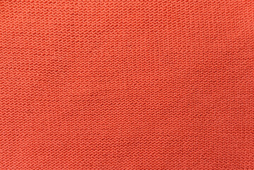 Knitted orange pattern closeup. Soft sweater texture, detailed yarn background. Natural woolen fabric, a fragment of a jersey pullover. Trendy backdrop for print, web design.