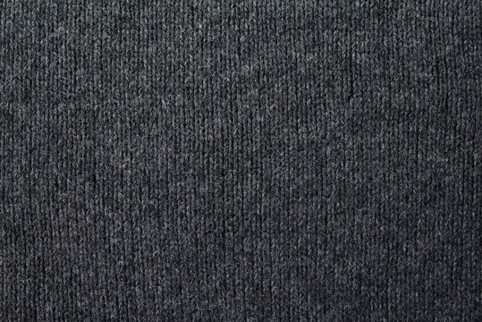 Knitted gray pattern closeup. Soft sweater texture, detailed yarn background. Natural woolen fabric, a fragment of a jersey pullover. Trendy backdrop for print, web design.