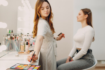 Beautiful young woman applying makeup beauty visage brush.