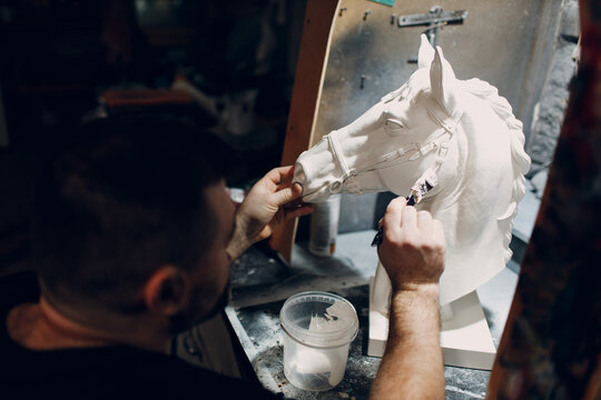 Artisan craftsman create horse based on plaster cast. Gypsum mold and plastic mask sculpting and painting