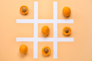 Tic tac toe game with ripe apricots and paper grid on color background