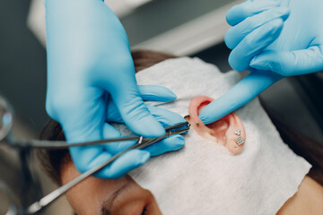 Young woman doing ear piercing at beauty studio salon