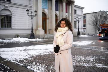 beautiful young black woman waiting in front of a theater for here friends in snow covered city 