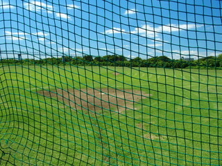 Obraz premium バックネット越しに見る夏の江戸川河川敷の野球場風景