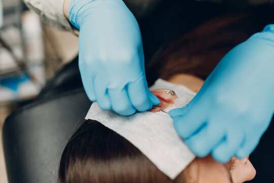 Young woman doing ear piercing at beauty studio salon