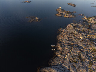 Aerial view of seascape with cliffs, calm sea and boats in sunset. Drone photography taken from above in summer in Sweden. Copy space.
