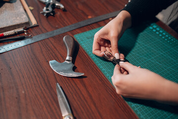 Tanner woman making leather goods on workshop. Working process of leather craftsman.