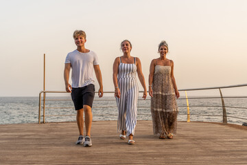 beautiful mother with her two twenty year old sons walking by the sea at sunset