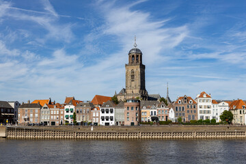 Fototapeta na wymiar Cityscape Dutch medieval city of Deventer in The Netherlands with the principal church and facades of historic homes seen from the other side of the river IJssel that passes it