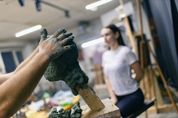 Man sculptor creates sculpt bust clay human woman model sculpture. Statue craft creation workshop...