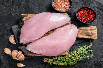 Uncooked Raw Turkey Breasts fillet steaks with herbs. Black background. Top view