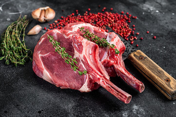 Raw Tomahawk rib veal steaks on butcher meat cleaver. Black background. Top view - obrazy, fototapety, plakaty