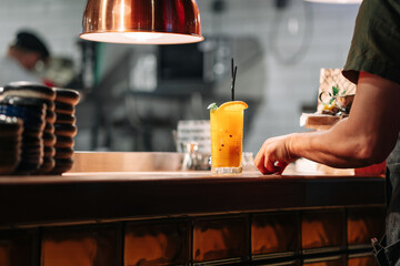 The waiter picks up the finished order from the distribution in the restaurant. Bright summer passionfruit cocktail