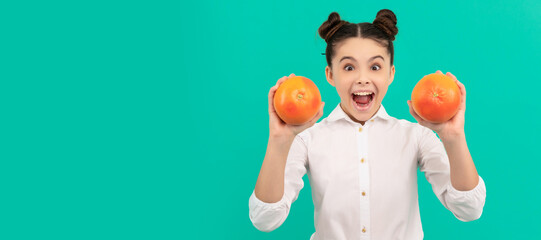 cheerful teen girl wear uniform holding grapefruit on blue background, vitamin. . Child girl...