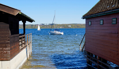 colorful boat houses on lake Ammersee with sailing boats and the Alps in the background in the Bavarian fishing village Schondorf (Bavaria, Germany)