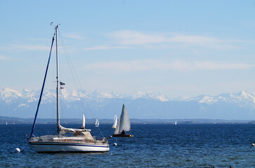 beautiful sailing boats on scenic and vast lake Ammersee with the snowy Alps in the background on a...