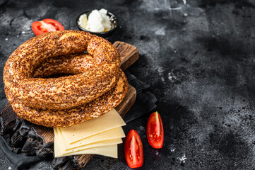 Bagel Simit or Gevrek on wooden board for cooking sandwich. Black background. Top view. Copy space