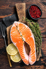 Fresh Raw Salmon trout Fish Steaks on wooden board with thyme and lemon. Wooden background. Top view