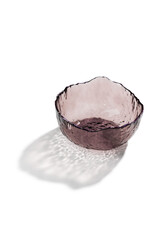 Close-up shot of a pink glass salad bowl with asymmetrical design and a purple rim edge. The empty...