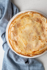 Stack of French crepes or traditional Russian blini on white plate on light background. Thin pancakes made from butter, eggs and milk. Traditional festival meal of Maslenitsa.