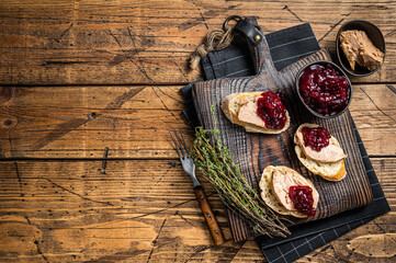 Fototapeta na wymiar French cuisine Foie gras toasts, goose liver pate and lingonberry marmalade. wooden background. Top view. Copy space