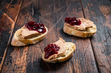French cuisine Foie gras toasts, goose liver pate and lingonberry marmalade. wooden background. Top...