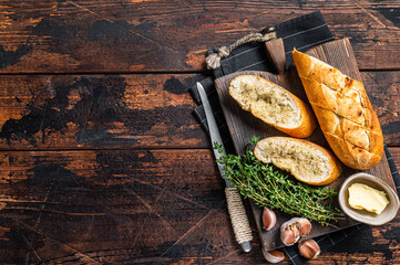 Toasted Garlic bread with herbs and butter on wooden cutting board. Wooden background. Top view....