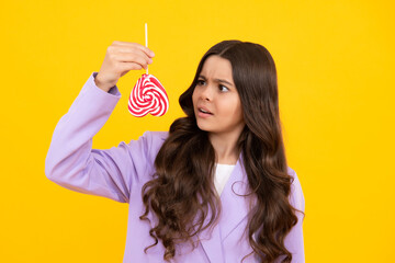 Teen girl hold lollipop caramel on yellow background, candy shop. Teenager with sweets suckers.