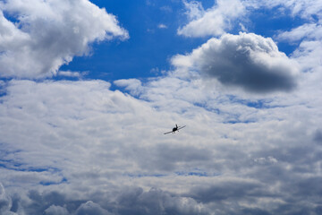 The plane is flying in the sky against the background of clouds