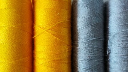 Yellow and gray coils with threads. Close-up of sewing threads.